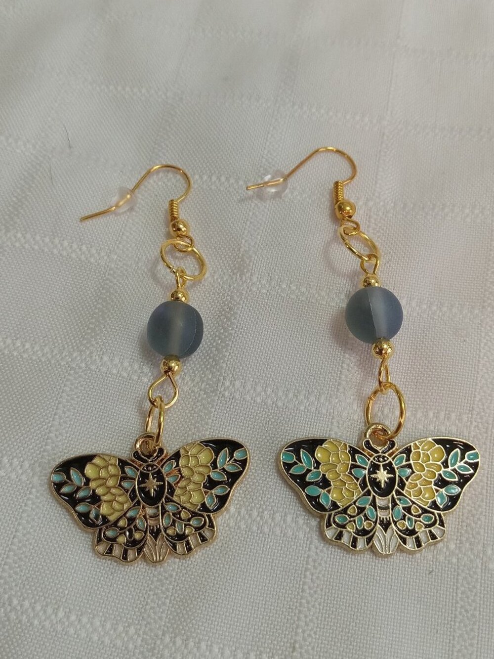 Handmade gold-colored earrings with multicolored enameled butterflies and beads
